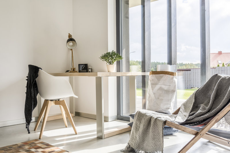 White room with deckchair, wooden desk, chair and window wall