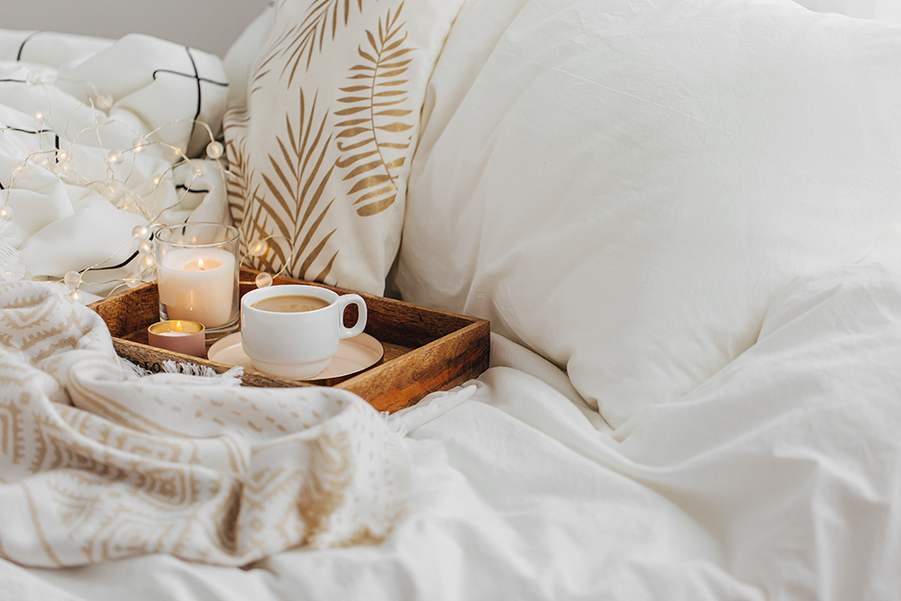 Cup of tea on tray. Placed on cosy duvet.