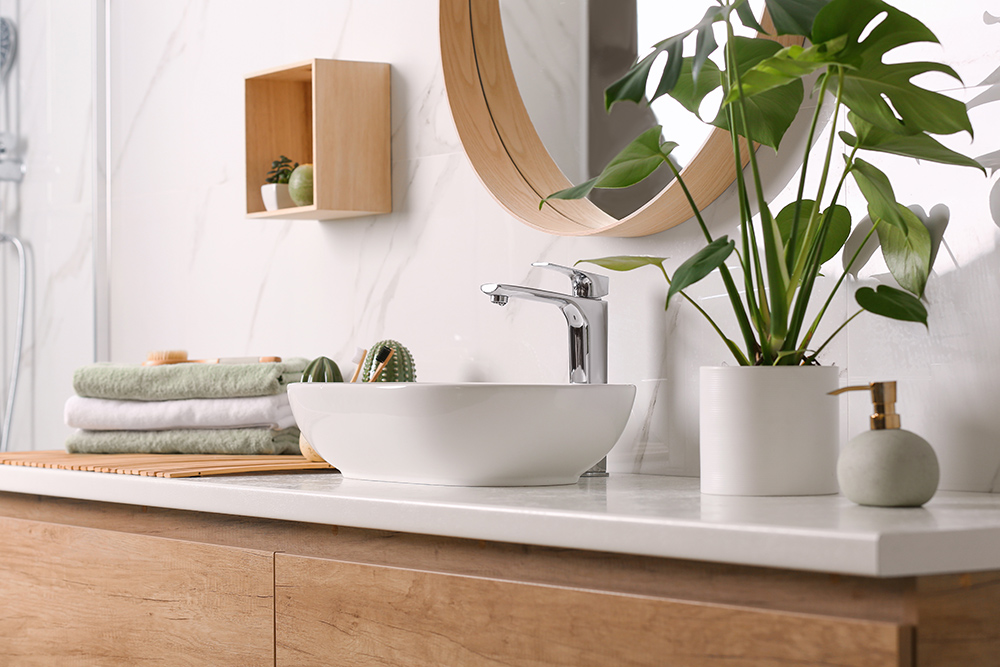 Relaxing bathroom with plants, round mirror, towels and soap.