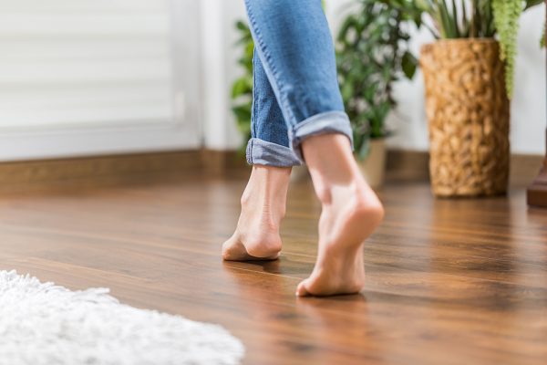 Women in blue jeans walking across wooden flooring
