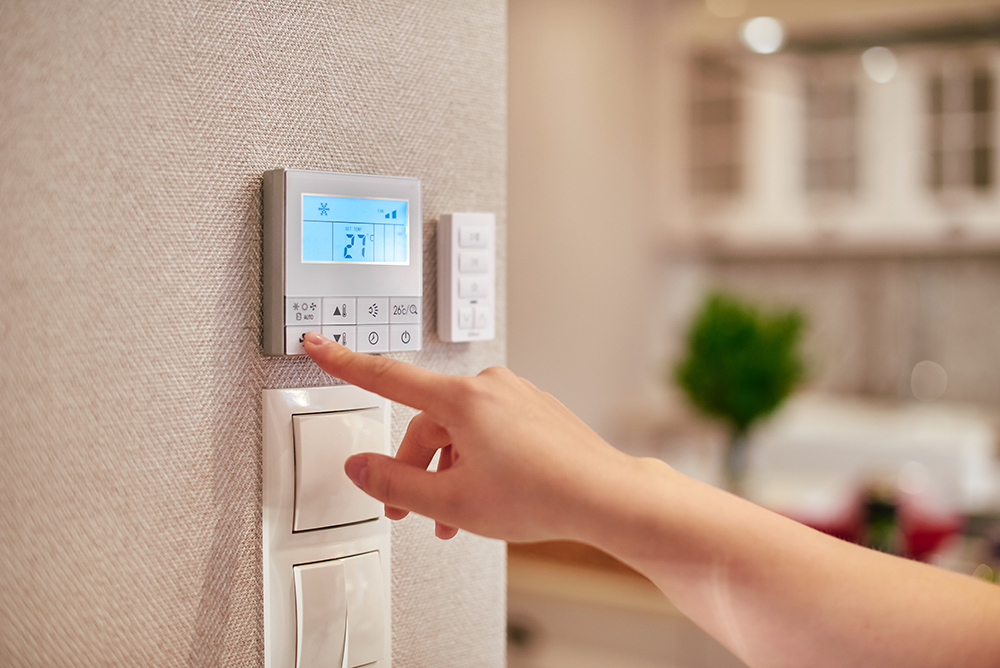 Woman programming temperature inside home via a thermostat