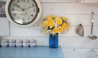 Rustic shabby chic kitchen with wall clock and yellow flowers in a blue vase