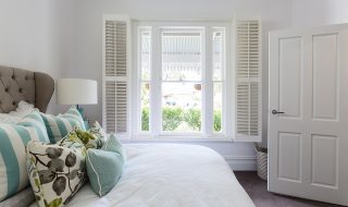 Stylish white bedroom with white shutters