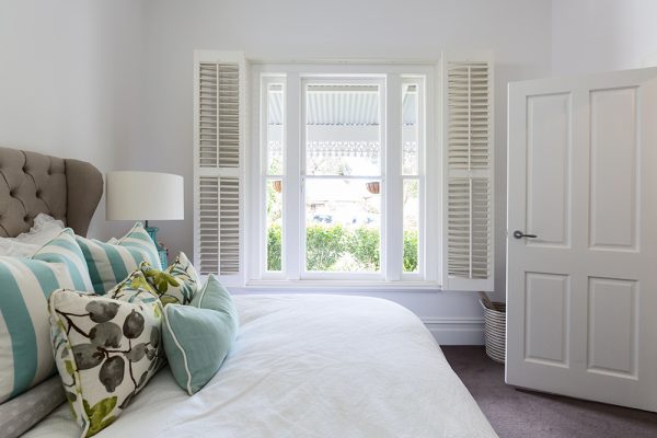 Stylish white bedroom with white shutters