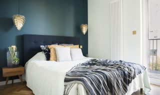 Blue and white small bedroom with wooden parquet flooring.