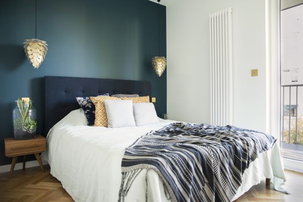 Blue and white small bedroom with wooden parquet flooring.