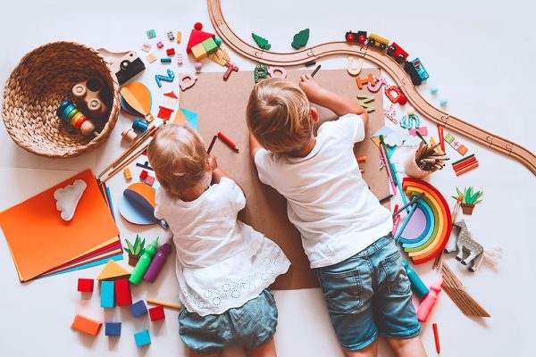 Children crafting and drawing with toys on the floor