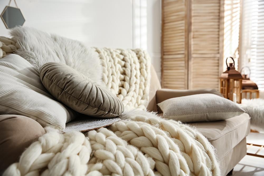 Cozy sofa with pillows and large knit cream coloured throw