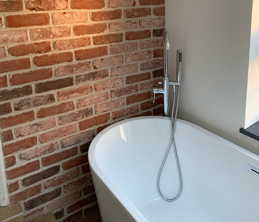 Bathroom with white stand alone bath and brick slip decorated balls
