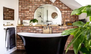 Stylish bathroom with black and white roll top bath. Walls decorated in brick slip tiles