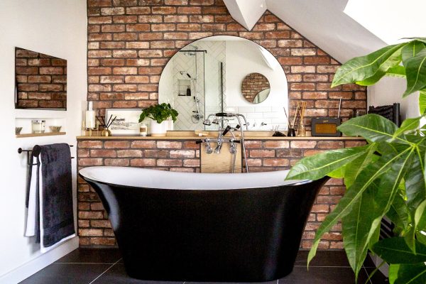 Stylish bathroom with black and white roll top bath. Walls decorated in brick slip tiles