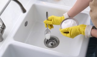 Woman using baking soda to unblock sink drain