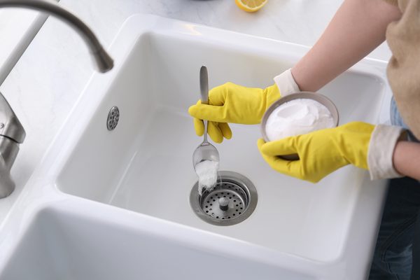 Woman using baking soda to unblock sink drain