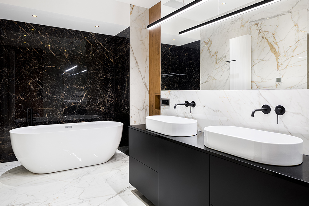 Black and white monochrome bathroom with white stand alone bath and black vanity unit with two white sinks