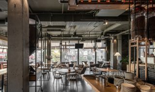 Modern coffee shop with industrial design inclucing metal, wood and concrete and large windows.