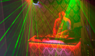 Dj usind decks surrounded by light show