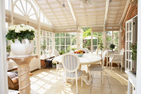 Large conservatory with ceiling blind, tiled flooring and ornate table and chairs