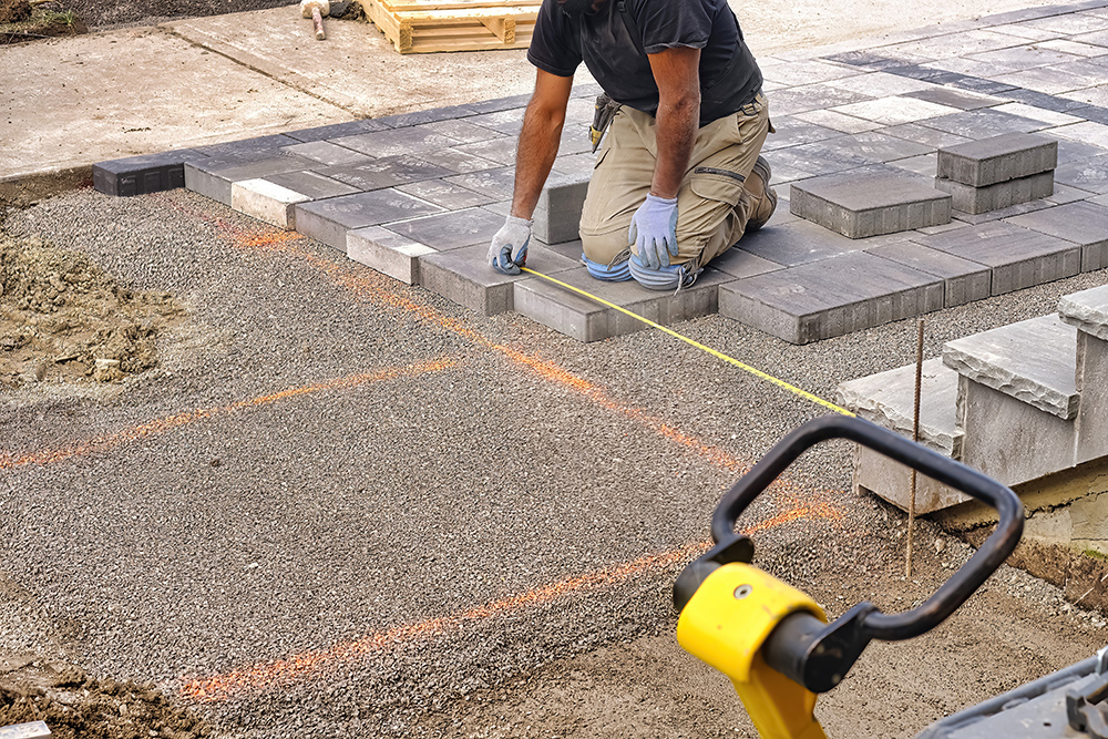 Construction worker placing grey stones on driveway