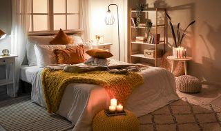 Bedroom with mustard colour throw, orange pillows and mood lighting with lamps and candles