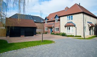 Large modern country home with red brick driveway and grey brick road