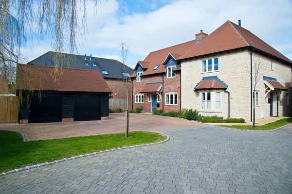 Large modern country home with red brick driveway and grey brick road
