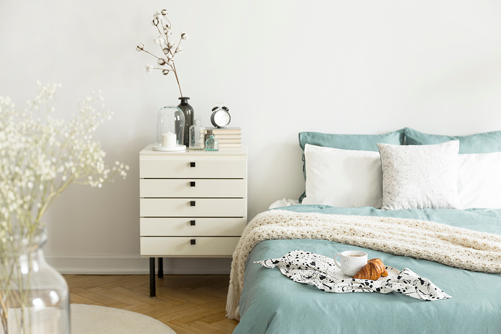 Natural bedroom with blue bedding and dried plants in a vase